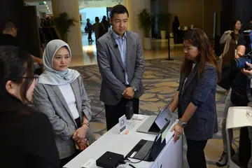 Menteri Negara (Penerangan dan Pembangunan Digital merangkap Kesihatan), Cik Rahayu Mahzam (dua dari kiri), meninjau peranti Windows 365 Link yang baru dilancarkan bagi pasaran Singapura sempena Hari Penyelesaian Sektor Awam Microsoft 2026 pada 9 April. Bersama beliau ialah Pengarah Urusan, Microsoft Singapore, Encik Wee Luen Chia.