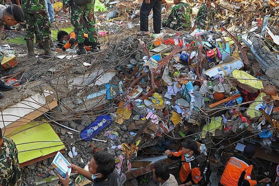GIGIH CARI MANGSA: Pasukan mencari dan menyelamat Indonesia sedang mencari mangsa di bawah timbunan runtuhan bangunan selepas kejadian gempa di Aceh awal pagi kelmarin. - Foto AFP 