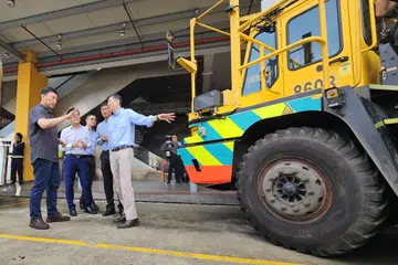 Menteri Pengangkutan, Encik Chee Hong Tat (kiri) diberi taklimat oleh Ketua Teknologi dan Penyelesaian Kemampanan PSA, Encik Alvin Foo (kanan), tentang usaha PSA menggunakan kenderaan kontena berautonomi.