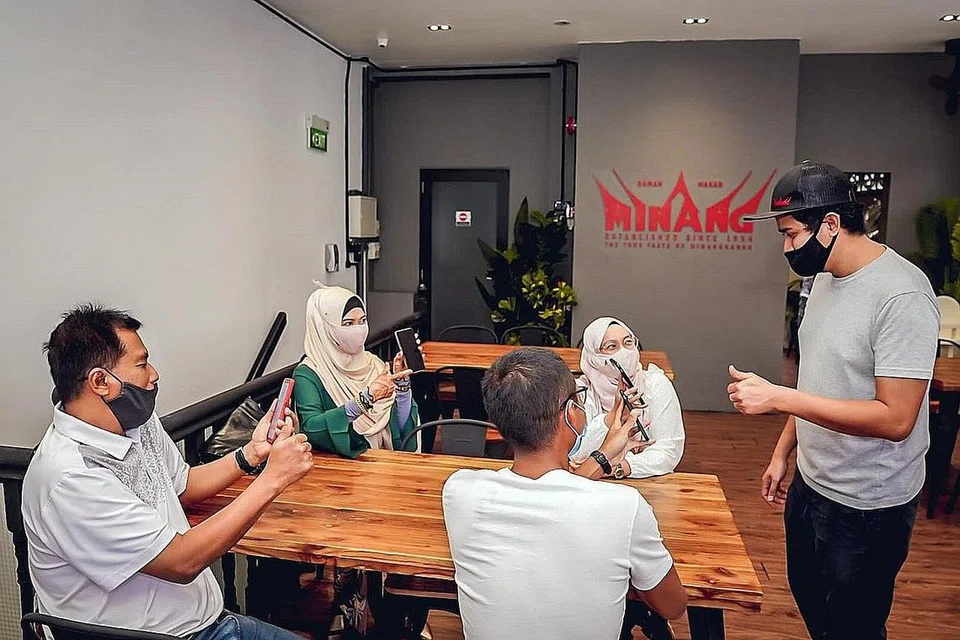 LAKUKAN PEMERIKSAAN: Kakitangan Rumah Makan Minang melakukan pemeriksaan demi memastikan status vaksinasi pelanggan sebelum mereka dibenarkan duduk bersama semalam. - Foto BH oleh NUR DIYANA TAHA
