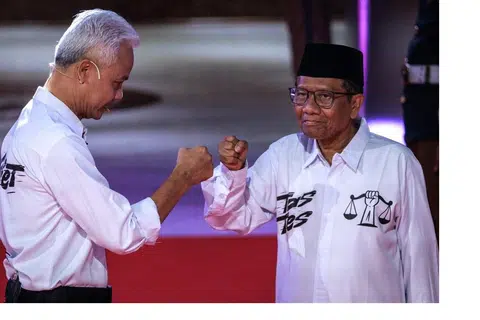 GIAT BERKEMPEN: Calon presiden dan mantan  gabenor Jawa Tengah, Encik Ganjar Pranowo (kiri), dan calon naib presiden Mahfud MD, bersapa ketika tiba untuk menghadiri perbahasan pilihan raya presiden pertama di pejabat Suruhanjaya Pilihan Raya Umum (KPU) di Jakarta pada 12 Disember 2023.
