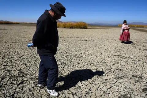 PANAS MELAMPAU: Penduduk dilihat berjalan di atas dasar Tasik Titicac, Bolivia, yang merekah dek suhu panas melampau.