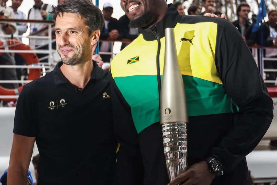 OBOR SUKAN OLIMPIK: Juara pecut Jamaica yang sudah bersara, Usain Bolt (kanan) membawa obor sukan Olimpik Paris 2024, dalam satu perarakan di pinggir Sungai Seine, dekat Menara Eiffel, pada Selasa.