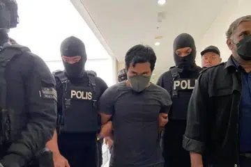Muhammad Sani Mahdi Sahar, 31 tahun (tengah), dikawal ketat polis ketika dibawa ke Mahkamah Sesyen Muar, Johor, untuk tuduhan di bawah Akta Kesalahan Keselamatan (Langkah-Langkah Khas) 2012 (Sosma) pada 13 Jun.