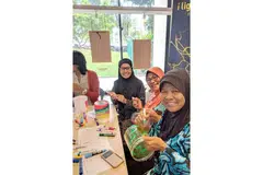 SUMBANG IDEA KREATIF: Cik Noriyah (bertudung jingga) bersama rakannya, Cik Sarimah Soeradi (berkaca mata) dan Cik Saharidah Suradi (berbaju biru), melukis bekas biskut PET mereka di bengkel prapesta di Jurong East bagi pemasangan seni lampu 'The Rainbow Connection'. - Foto BH oleh ZULAIQAH ABDUL RAHIM