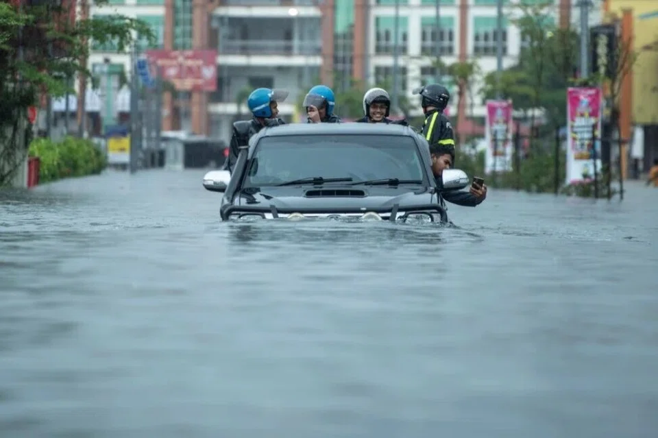 Penunggang motosikal keluar dari kawasan banjir di Pengkalan Chepa, Kelantan dengan menaiki kenderaan pacuan empat roda.