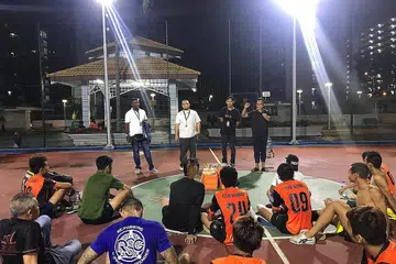 GABUNG TENAGA DEKATI BELIA: Encik Iqbal, pengasas Revive.sg (menghadap kamera, dua dari kiri), dan Encik Noor Halis, pengasas bersama One Heart Brothers Society (menghadap kamera, kanan), turun padang dalam acara futsal melibatkan remaja dan belia di estet perumahan Jalan Kukoh pada 11 November lalu. - Foto REVIVE.SG