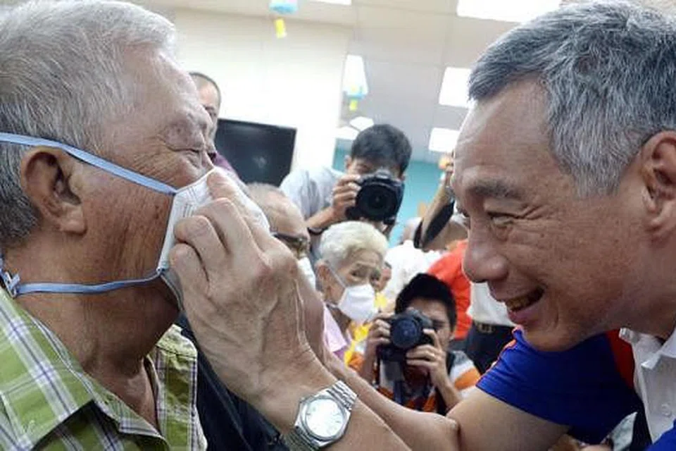 TUNJUK CARA BETUL: Encik Lee menunjukkan cara betul memakai pelitup kepada seorang warga tua di COMNET@Pusat Aktiviti Warga Emas Teck Ghee di Ang Mo Kio semalam. - Foto TAUFIK A. KADER