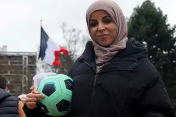 LAKUKAN PROTES: Cik Majid Siham memegang bola semasa perhimpunan bagi menyokong pasukan bola sepak wanita ‘Les Hijabeuses’ di hadapan bangunan bandar raya Lille sebagai membantah rang undang-undang mengharamkan pemakaian hijab dalam acara sukan.