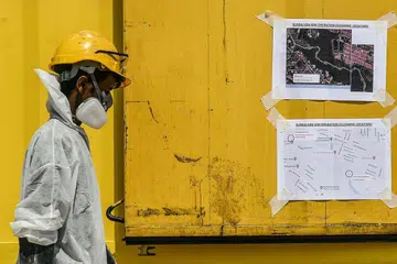 MASIH ADA LAGI TAPAK YANG TERCEMAR: Seorang kakitangan kecemasan dengan pakaian perlindungan di lokasi kerja pembersihanan di Sungai Kim Kim, Pasir Gudang. Pemeriksaan akhbar setempat menunjukkan ada tanda-tanda baru tapak pembuangan sisa lain dalam kawasan lima kilometer sungai itu. - Foto EPA-EFE
