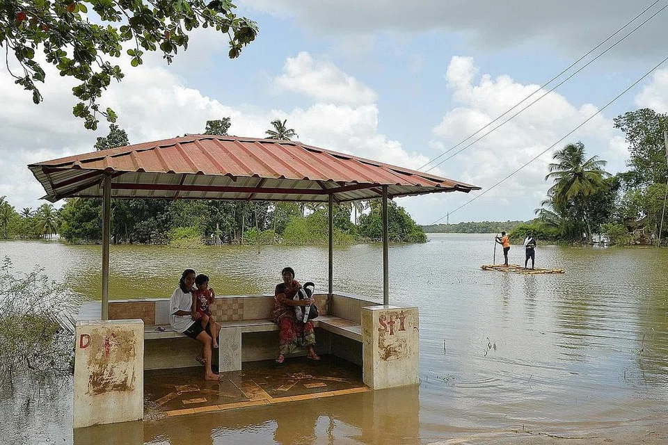 JALAN DINAIKI AIR: Penduduk di daerah Pandanad, di Kerala, duduk di sebuah stesen bas yang dikelilingi air banjir, sambil menantikan rakit yang digunakan sebagai pengangkutan. - Foto AFP 