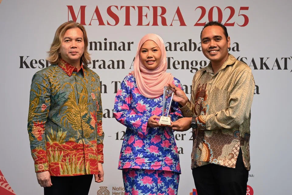 Pemenang Hadiah Terjemahan Majlis Sastera Asia Tenggara (Mastera) 2025, Cik Fathiah Jamal (tengah), menerima anugerah tersebut daripada Pengerusi Majlis Bahasa Melayu Singapura (MBMS), Encik Zhulkarnain Abdul Rahim (kanan), dan Pengerusi Mastera Singapura dan Naib Pengerusi MBMS, Dr Azhar Ibrahim, semasa majlis perasmian Mastera 2025 yang diadakan di The Pod, Bangunan Perpustakaan Negara (NLB) pada 10 September.