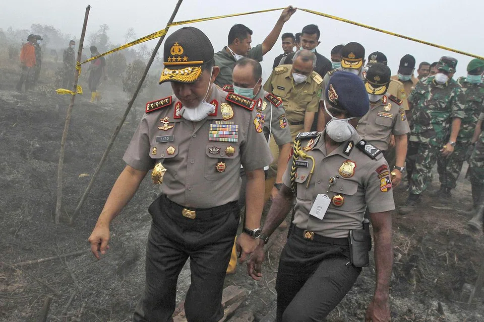 MEMANTAU KEBAKARAN BELUKAR: Ketua Polis Indonesia, Jeneral Tito Karnavian (kiri), dan kakitangannya memeriksa tanah gambut dan kebakaran hutan. - Foto AFP