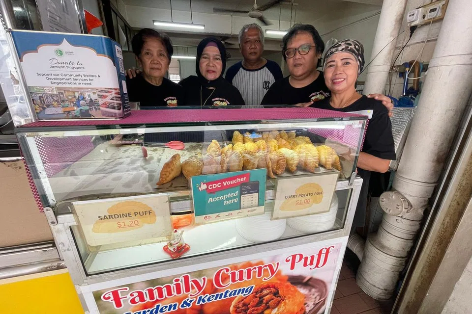 RAIH MANFAAT: Cik Zawiah Zainol (kanan) bersama ahli keluarga beliau menguruskan gerai epok-epok mereka, Family Curry Puff, di North Bridge Road dan menawarkan kemudahan kepada para pelanggan menggunakan Baucar CDC untuk membeli epok-epok mereka.