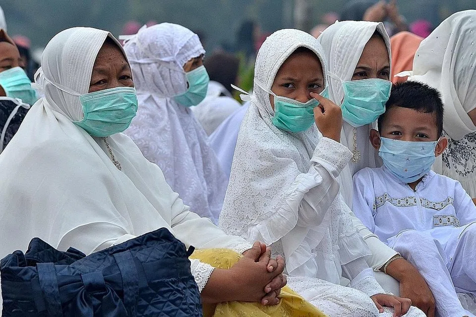 MENGENAKAN PELITUP: Satu keluarga yang berkumpul untuk solat Aidiladha di Masjid An Nur, Pekanbaru, Riau, Ahad lalu perlu mengenakan pelitup akibat keadaan berjerebu. - Foto Reuters