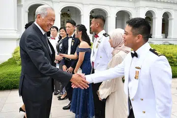 BERJABAT TANGAN: Dr Ng (kiri) berinteraksi dengan lulusan terbaik bersama pasangan mereka di Kolej Komand dan Staf Goh Keng Swee kelmarin. - Foto MINDEF