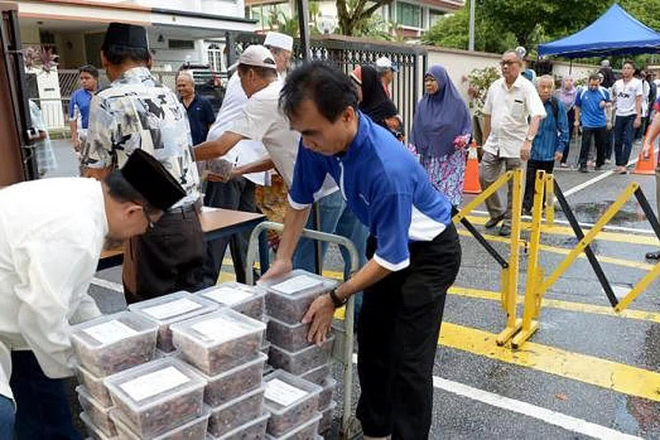 DAPATKAN KURMA: Orang ramai beratur sejak 8.30 pagi Ahad lalu bagi mendapatkan kurma di Masjid Ba'alwie. - Foto TUKIMAN WARJI