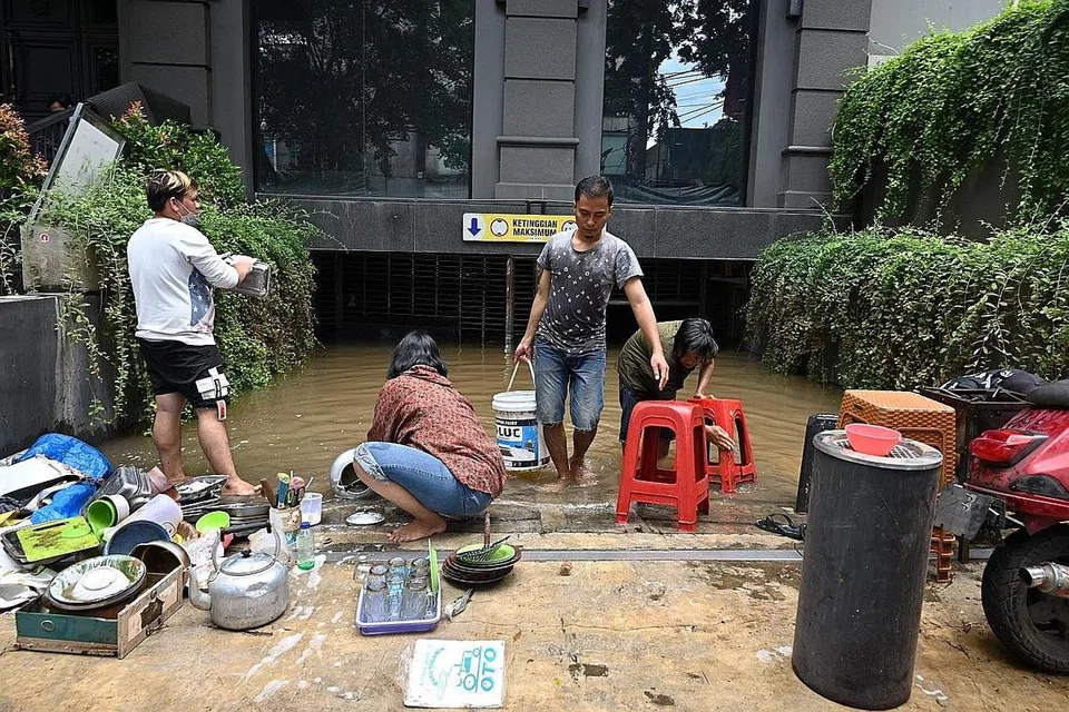 SELEPAS BANJIR: Penjaja di tepi jalan membersihkan lumpur dari perkakas mereka kelmarin, sehari selepas beberapa kawasan di ibu kota Jakarta dilanda banjir. - Foto AFP