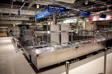 KEMUDAHAN TERSEDIA: Dewan makan utama (atas) yang akan menyajikan pelbagai pilihan makanan, termasuk halal. Atlet, yang tidak dibenarkan keluar dari Kampung Sukan kecuali ke tempat pertandingan atau pusat latihan, dikehendaki makan sendirian. Kampung sukan itu dibina untuk menampung hingga 18,000 atlet, jurulatih dan pegawai. Bilik individu sebesar 9 meter persegi, manakala bilik pasangan 12 meter persegi. - Foto AFP