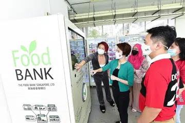 BANTU PENDUDUK MEMERLUKAN: Datuk Bandar CDC South West, Cik Low Yen Ling, dan penasihat Pertubuhan Akar Umbi GRC Chua Chua Kang (Brickland), Encik Don Wee, semasa melancarkan mesin layan diri bank makanan di Blok 813A, Choa Chu Kang Avenue 7 pada Sabtu lalu. - Foto oleh CDC SOUTH WEST