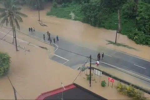 ENTAH KE MANA: Beberapa remaja kelihatan berdiri di jalan raya yang dinaiki air di Taman Aman, Kota Kecil, Kota Tinggi.