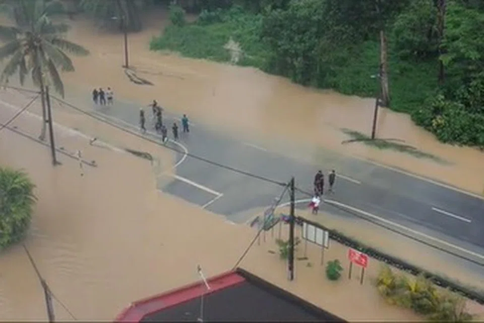 ENTAH KE MANA: Beberapa remaja kelihatan berdiri di jalan raya yang dinaiki air di Taman Aman, Kota Kecil, Kota Tinggi.