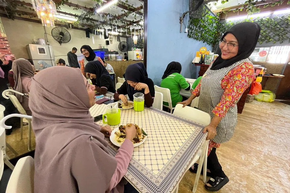 Pemilik Hanie’s Cafe, Cik Darish Hanie Hatta, 47 tahun (kanan), ramah melayan pelanggan di kedainya di Sungai Buloh, Selangor.
