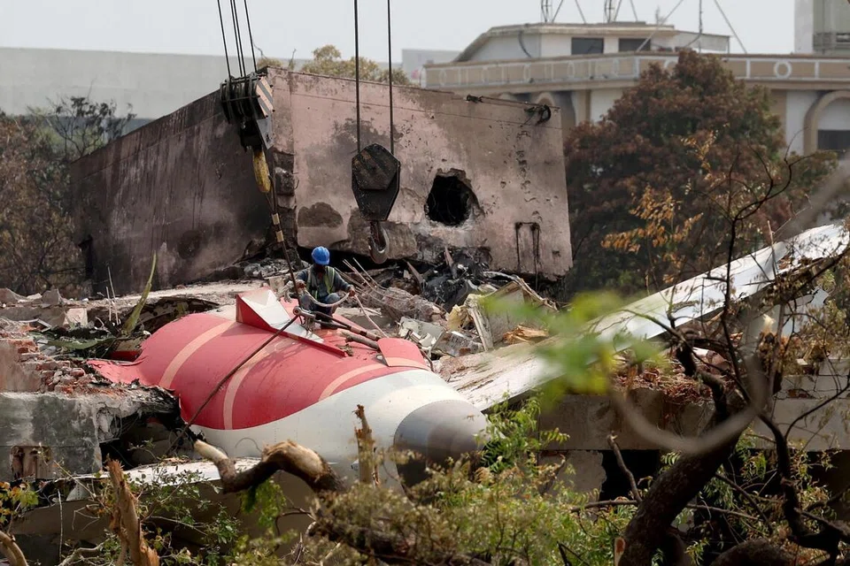 Seorang lelaki bersiap untuk mengalihkan bangkai pesawat, Air India Boeing 787-8 Dreamliner, yang terhempas ketika berlepas dari lapangan terbang di Ahmedabad, India, pada 14 Jun.