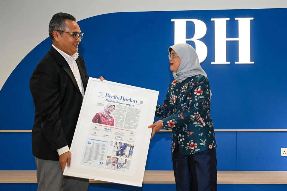 HARGAI SUMBANGAN: Editor BH, Encik Nazry Mokhtar menyampaikan cenderahati tanda penghargaan kepada Puan Halimah yang berupa contoh halaman pertama akhbar ‘Berita Harian’ khusus baginya. 