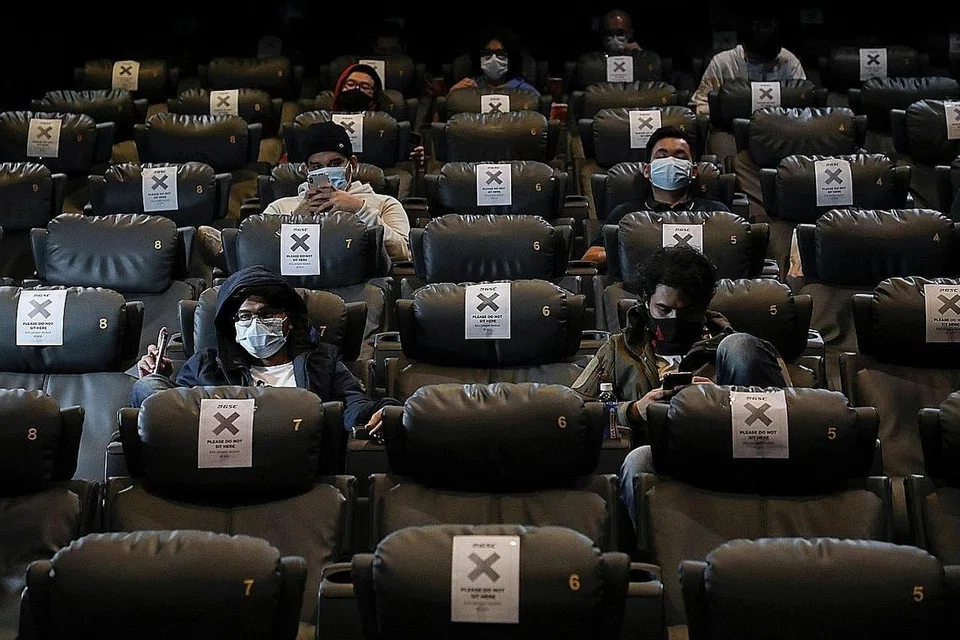 GUNAKAN PELITUP DI PAWAGAM: Penonton mengenakan pelitup muka dan dalam masa yang sama mematuhi arahan jarak selamat semasa menonton filem di Golden Screen Cinemas, selepas pawagam dibuka semula di Kuala Lumpur baru-baru ini. - Foto REUTERS