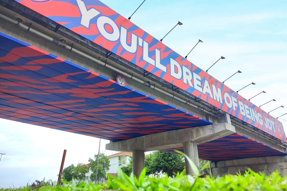 SIAP PENUH: Jambatan kereta api melintang Jalan Skudai - Gelang Patah kelihatan diliputi penuh dengan warna belang merah biru pasukan Harimau Selatan, Kelab Bola Sepak Johor Darul Ta’zim.