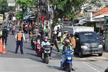 BUAT PEMERIKSAAN: Polis memeriksa kereta di pusat pemeriksaan di Jakarta semalam. Jakarta telah melaksanakan langkah jarak selamat yang ketat demi membendung penularan Covid-19. - Foto AFP 