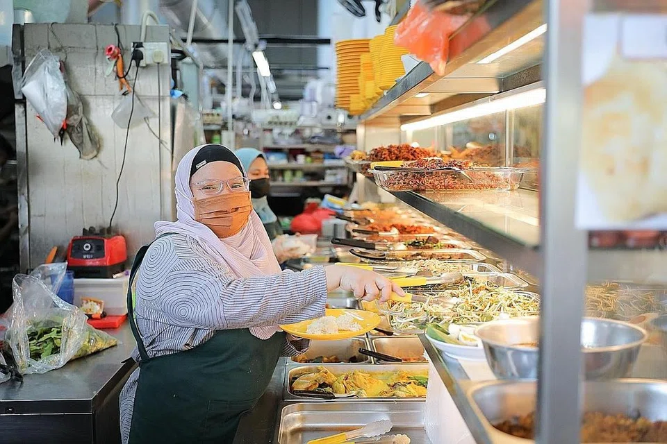 MAHU TERUS BERTAHAN: Walaupun perniagaannya mengalami kerugian besar, Cik Khadijah Mukhit memastikan harga makanannya rendah dan terus dimampui untuk menarik pelanggan. - Foto BM oleh ONG WEE JIN