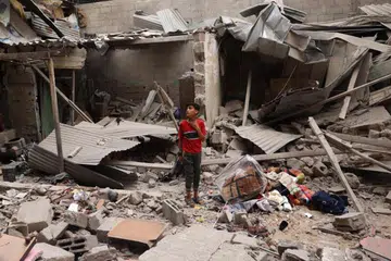 Seorang kanak-kanak Palestin berdiri di tengah-tengah serpihan sebuah rumah yang musnah susuli serangan semalaman di Rafah pada 27 April. 