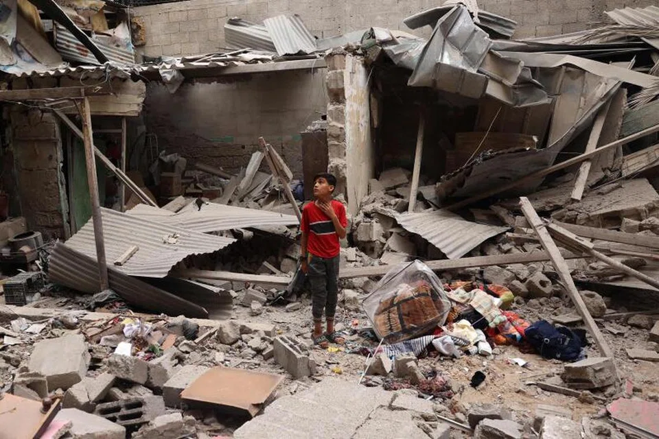 Seorang kanak-kanak Palestin berdiri di tengah-tengah serpihan sebuah rumah yang musnah susuli serangan semalaman di Rafah pada 27 April. 