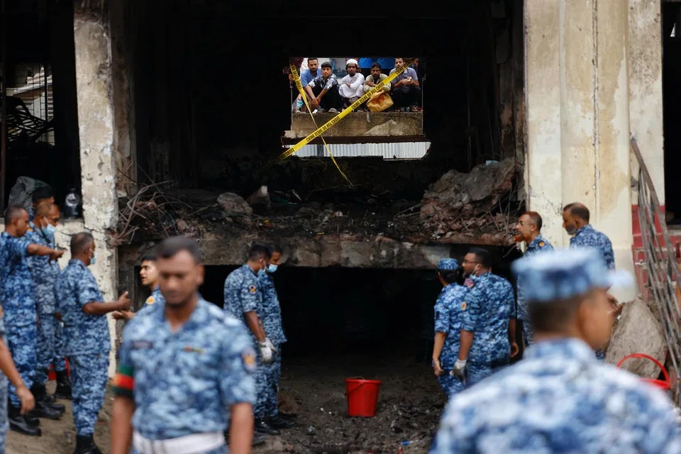 Orang ramai memerhati melalui tingkap yang pecah ketika anggota Tentera Udara Bangladesh menjalankan operasi di lokasi kejadian, selepas sebuah pesawat latihan tentera terhempas ke sebuah bangunan milik kampus Milestone School and College di Dhaka, Bangladesh, pada 22 Julai 2025. 