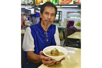 HASIL BERNIAGA: Encik Amran Zakaria boleh menarik nafas lega kerana minat dan pengorbanannya sejak zaman remaja menguatkan tekadnya mahu terus berniaga makanan yang menjadi sumber rezeki keluarganya sehingga ke hari ini. - Foto BH oleh DESMOND WEE
