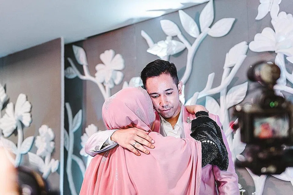 DAKAPAN BUAT IBU: Sufi memeluk ibunya, Irma Suriana Mahamud, yang hadir di majlis persandingannya di Kelab Perkhidmatan Awam Changi, Sabtu lalu. Sebelum ini, kisah ketegangan hubungan ibu dan anak timbul kerana isteri pilihan Sufi. - Foto BH oleh KHIDHIR ASYRAF MAHBOB