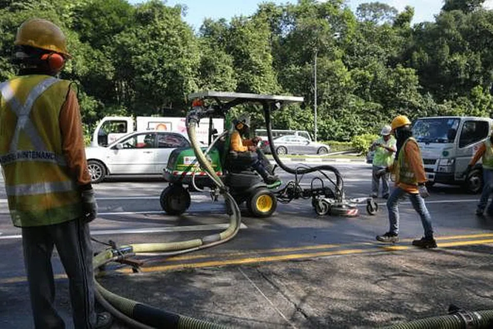 TUMPAHAN MINYAK KEEMPAT: Pekerja dilihat sedang membershikan minyak yang tumpah di Lornie Road ke arah Adam Road pagi semalam. - Foto THE STRAITS TIMES