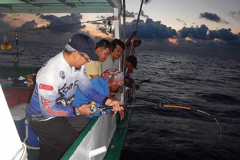 'BERLAWAN' DENGAN IKAN: Beberapa anggota kumpulan Komplot bagai berlawan dengan ikan semasa mereka memancing sambil disaksikan teman-teman dalam suasana laut terbentang luas.