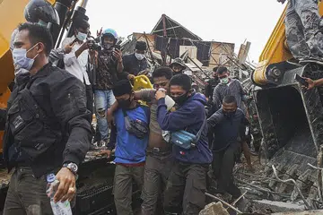 DISELAMATKAN: Seorang mangsa dikeluarkan daripada runtuhan bangunan pemerintah selepas gempa melanda Mamuju, Sulawesi Barat, kemarin. - Foto EPA-EFE