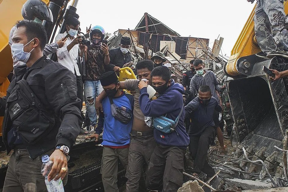 DISELAMATKAN: Seorang mangsa dikeluarkan daripada runtuhan bangunan pemerintah selepas gempa melanda Mamuju, Sulawesi Barat, kemarin. - Foto EPA-EFE