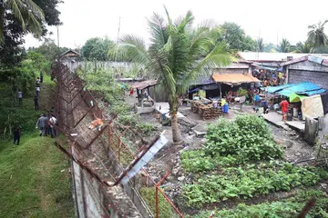 MEMERIKSA: Pegawai penjara (kiri) memeriksa pagar penjara setelah lebih 130 banduan melarikan diri dari penjara yang terletak di Kidapawan di bahagian selatan Mindanao semalam ketika militan menyerang penjara tersebut dan membunuh seorang pegawai. - Foto AFP