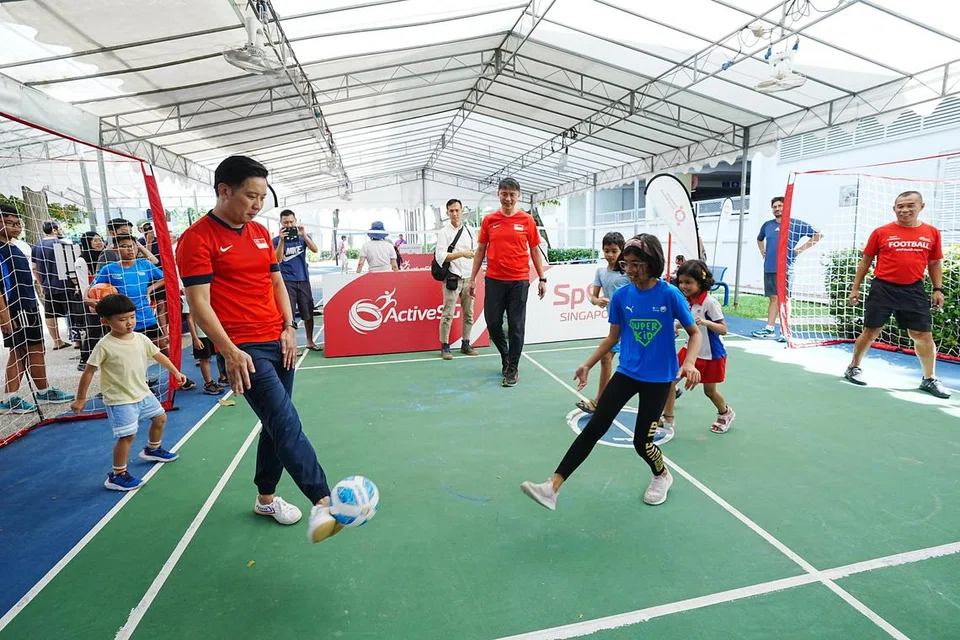 Menteri Negara (Kebudayaan, Masyarakat dan Belia merangkap Perdagangan dan Perusahaan), Encik Alvin Tan bermain bola bersama beberapa kanak-kanak yang hadir ke acara tersebut di samping bekas pemain bola sepak negara Lim Tong Hai (tengah) dan Steven Tan (kanan). 