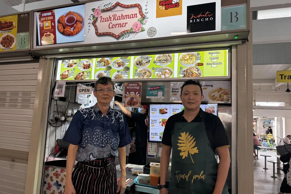 Encik Affandi Abdul Rahman, 44 tahun (kanan), bersama ayah beliau, Encik Abdul Rahman Suradi, 70 tahun. Mereka berdua memiliki sebuah gerai di Marine Parade dan telah menikmati peningkatan jualan sebanyak 20 peratus sejak memanfaatkan  skim pembayaran menerusi baucar Majlis Pembangunan Masyarakat (CDC) sejak 2021.