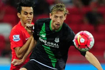 KAWAL BOLA: Penyerang Stoke City, Peter Crouch (depan), mengawal bola daripada cuba diadang oleh pemain pasukan Pilihan Singapura, Shahdan Sulaiman.