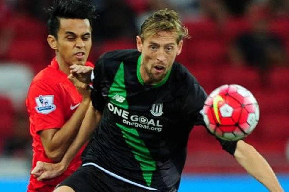 KAWAL BOLA: Penyerang Stoke City, Peter Crouch (depan), mengawal bola daripada cuba diadang oleh pemain pasukan Pilihan Singapura, Shahdan Sulaiman.
