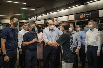 TEMUI PENUMPANG: Menteri Pengangkutan, Encik S Iswaran, yang hadir selaku tetamu terhormat di acara pembukaan TEL3 semalam, beramah mesra dengan seorang penumpang semasa kunjungannya di stesen Havelock. - Foto BH oleh GAVIN FOO