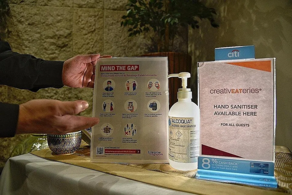 LANGKAH SELAMAT: Restoran Patara Fine Thai Cuisine di Tanglin Mall menyediakan sanitiser tangan dan meletakkan tanda tentang langkah jarak selamat di pintu masuknya. - Foto BH oleh DESMOND WEE