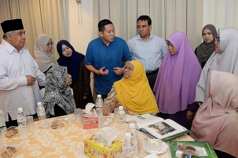 ADAKAN PERBINCANGAN: Encik Amrin (tengah berbaju biru) berbincang dengan Ustaz Ali Haji Mohamed (kiri), dan anggota RRG yang lain yang menghadiri forum mengenai pengganasan di Masjid Khadijah. - Foto fail